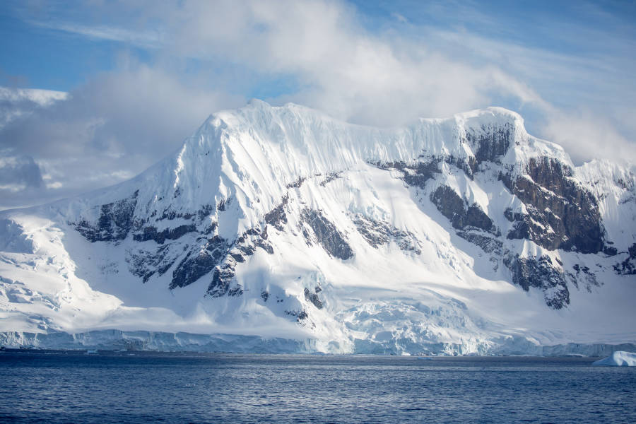 A snow covered mountain emerging from the Antarctic ocean
