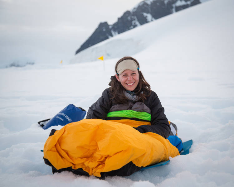 One of our guests smiles for a photo in theie bivvy bag as they wake up after overnight camping in Antarctica.