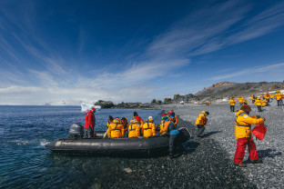 Expedition Guides help guests get out of their zodiac boats on a rocky beach at Half Moon Island.