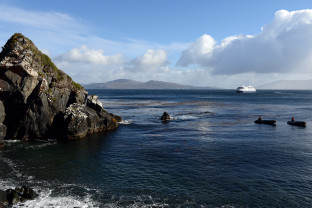 Zodiac boats pass by a rock formation at Cape Horn.