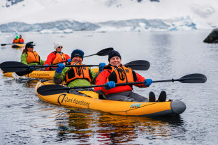 Two guests in dry suits paddle through Antarctic waters onboard our sit-on-top inflatable kayaks.