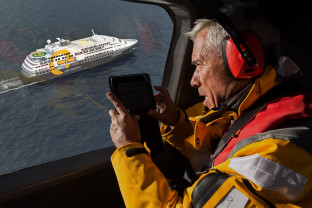 A guest takes photos of the ship Ultramarine while helicopter flightseeing.