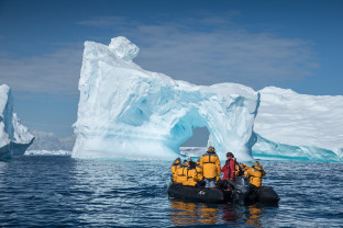 Eleven guests and an Expedition Guide witness a massive iceberg as they stop at a safe distance to capture photographs