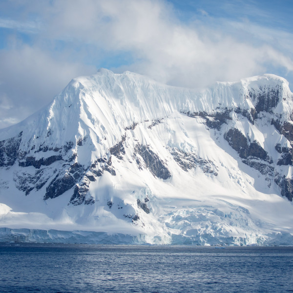 A snow covered mountain emerging from the Antarctic ocean